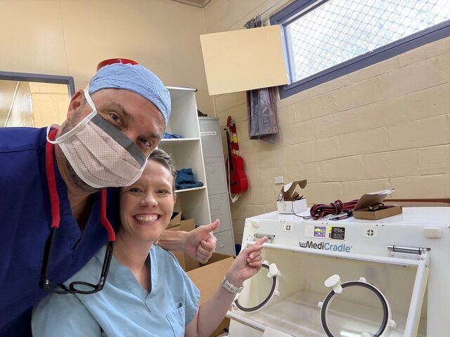 Doctor in scrubs comforting a pediatric patient before medical care.
