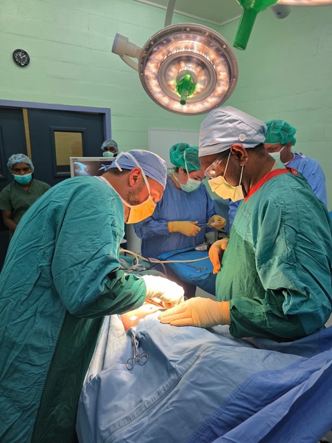 Surgeons in full protective gear performing specialized pediatric surgery.
